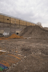 Recycling of concrete industrial wasteland large piles of concrete granulate in front of old masonry portrait format
