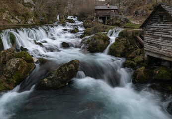 Fototapeta na wymiar Mountain river with mossy rocks and wooden watermills in long exposure, river Krupa in Krupa na Vrbasu