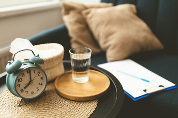 Psychologist's office. Close-up of glass of water, clock and napkins on sofa. Comfortable sofa. Atmosphere for a psychotherapy session. Treatment of depression.
