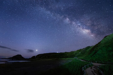 Fototapeta na wymiar 浜辺の丘に明けの明星と天の川が輝く