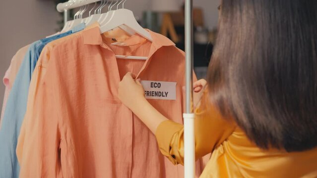 Female seller putting eco friendly label on blouse, sustainable fibers clothing
