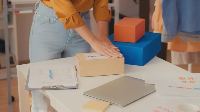 Seller putting sustainable label on box before delivery, eco friendly business