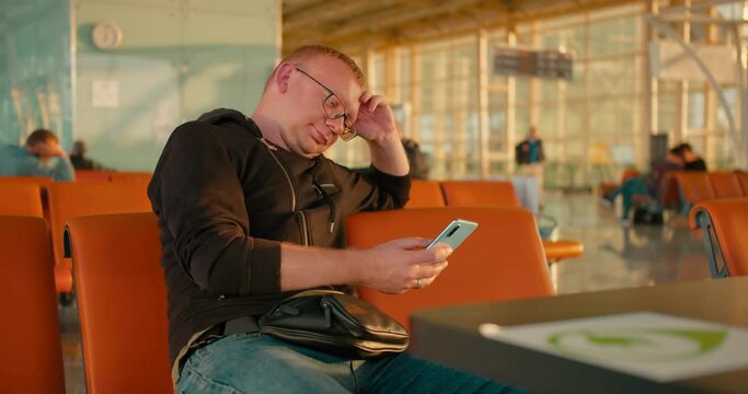 Man use of smart phone in the airport lounge, medium shot