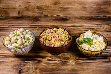 Set of festive mayonnaise salads on wooden table