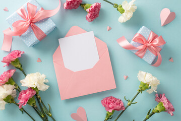 Mother's Day joy concept. Top view flat lay photo of open blank envelope beautiful present boxes with pink ribbons, carnation flowers, and pink paper hearts on pastel blue background