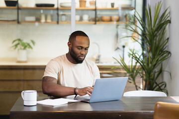 Young business black african american man working from home on table with notebook computer laptop