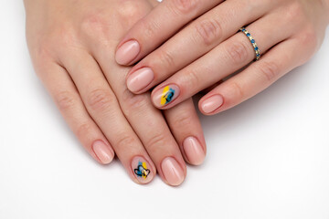 Natural beige manicure on short oval nails. Ukrainian symbols. Yellow blue drawing.