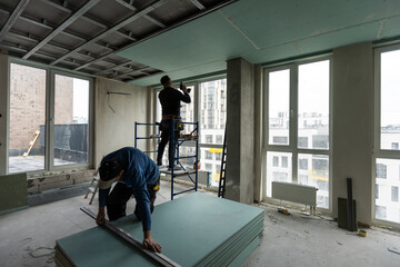 Ceiling installation with expert technicians In the room that is in the construction process - obrazy, fototapety, plakaty