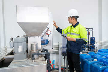 Asian engineer or electrician checking electrical system Working principle of the water supply control cabinet with tablets at the factory.