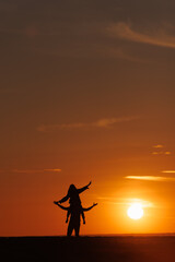 silhouettes of couple at sunset against bright sun sky. man and woman have fun in nature, walking and relaxing, relationships and falling in love. poster postcard romantic meetings against background 