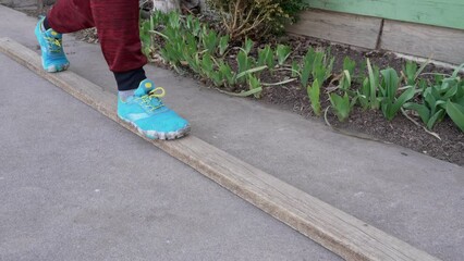 balance exercise - feet of a man walking back and forth and practicing lunges on a wobbly 2x4 lumber in a backyard