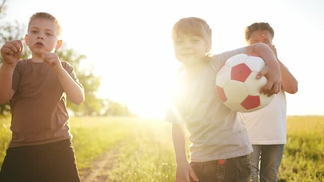 Children are walk in the park. A team of young athletes go to training with a ball game in the park. children walk carry ball and create a team. Games in the park. happy family fun kid dream concept