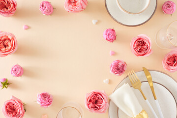 Setting table concept for Mother's Day. Flat lay composition of plate cutlery knife fork napkin cup and saucer flowers pink rose buds and small hearts on light beige background with empty space