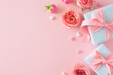 Present concept for Mother's Day. Top view photo of gift boxes natural flowers pink rose buds and small hearts on isolated light pink background with empty space
