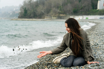 Young beautiful brunette woman sitting on sea shore alone.