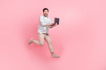 Full length photo of cheerful excited man wear turquoise shirt chatting modern gadget empty space isolated pink color background