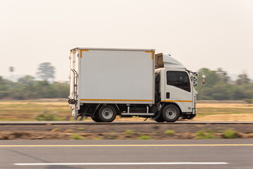 Fototapeta na wymiar Small truck driving on the highway, Small white delivery truck moving fast on road, distribution business express delivery service