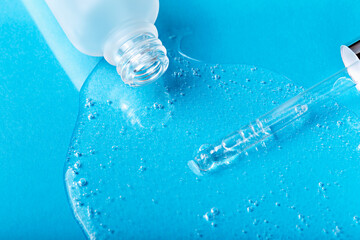 Laboratory studies. Dropper with clear liquid and glass white cosmetic bottle on blue background...