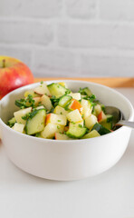 Raw fruit and vegetable salad with cubed cucumber and apples marinated with honey, lemon juice, olive oil and parsley