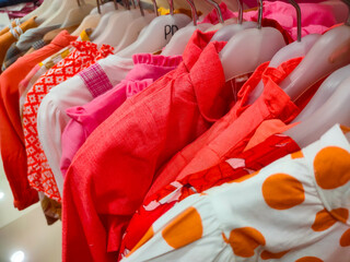 Colorful t-shirt hanging on the rack in fashion department store at shopping mall. Fashionable brand new for sale - interior of cloth store
