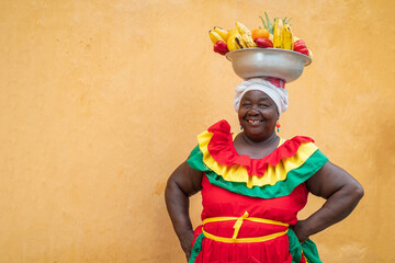 Cheerful fresh fruit street vendor aka Palenquera in the Old Town of Cartagena de Indias, Colombia. Happy Afro-Colombian woman in traditional clothing, Colombian culture and lifestyle.	