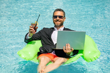 Summer business dreams. Millennial business man in suit floating with cocktail and laptop in...