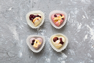 chocolate sweets in the form of a heart with fruits and nuts on a colored background. top view with space for text, holiday concept
