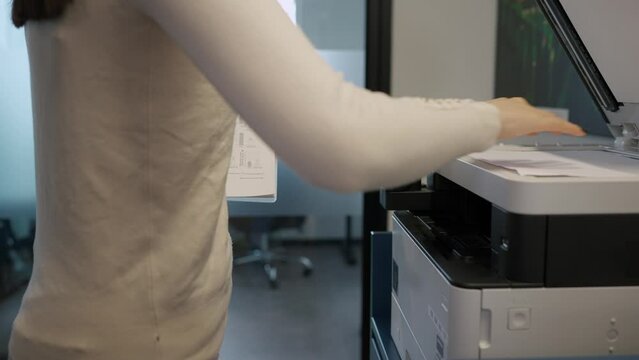 Faceless woman printing documents on printer in office