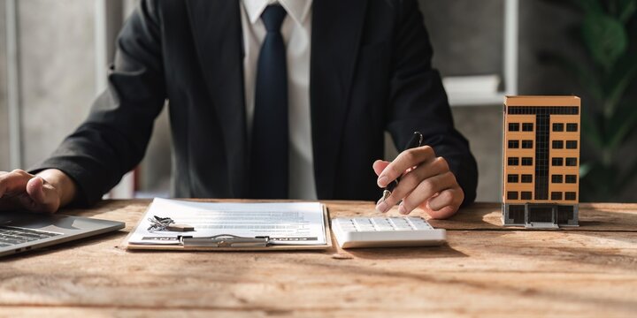 Bank Loan Workers Are Using Calculators To Calculate Home Loan Interest Rates For Customers To Assess Their Investment Capabilities Using Key Document