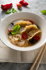 Spicy miso soup with dumplings and rice noodles in white bowl