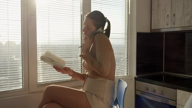 Young woman taking notes in notebook while talking by phone. Concept of education, female working in office, finding job