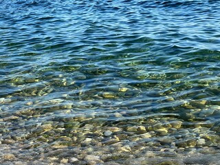 Clear water sea stones pebbles at the seabed, rippled waves, beautiful seascape.