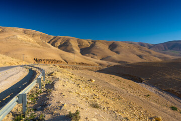 Z Madaby nad Morze Martwe w Jordanii. Pustynny krajobraz z widokiem na wzgórza i piękne bezchmurne niebo.  - obrazy, fototapety, plakaty