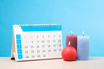 Desk calendar with flaming candles on the table, blue background © splitov27