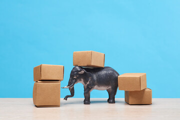 Elephant toy model with cardboard boxes on a blue background. Shopping, delivery concept