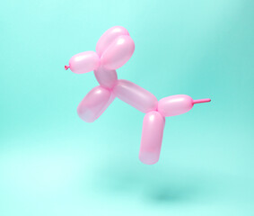Pink balloon in the shape of dog levitating on blue background.