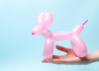 Woman's hand holding balloon dog on blue background