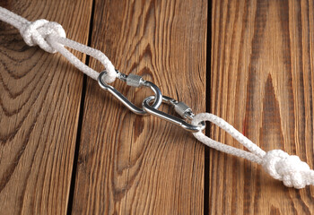 Rope with knots and carabiners on wooden boards. Safety, climbing equipment