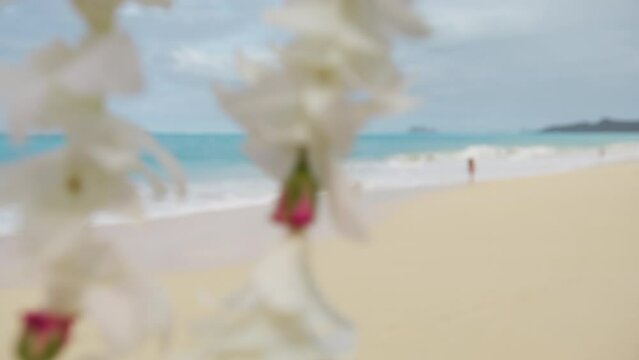 Close up first-person view on white tropical flowers on traditional Hawaiian Lei necklace. Process of traditional welcoming tourist guest on Hawaii islands with scenic white sandy beach landscape 4K