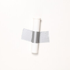 Pills tube fixed with adhesive tape on white background. Conceptual pop, contemporary art, minimalist still life