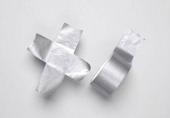 Roll of metallic duct tape with cross tape on white background. Top view