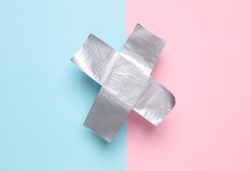 Cross stripes metallic adhesive tape on pink blue background. Top view