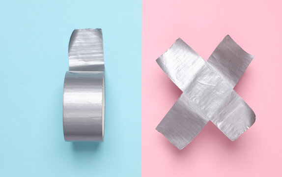 Roll of metallic duct tape with cross tape on pink blue background. Top view