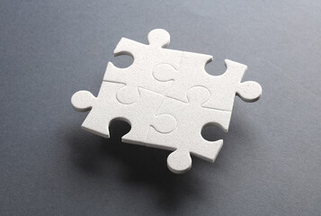 Obraz premium White jigsaw puzzle pieces on dark background.