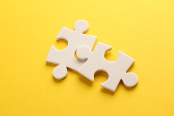 Fototapeta premium White jigsaw puzzle pieces on yellow background.
