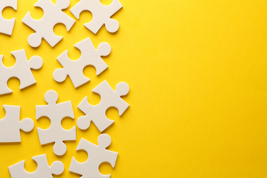 White jigsaw puzzle pieces on yellow background.