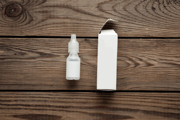 Bottle of eye drops with packaging on a wooden table. Template for design