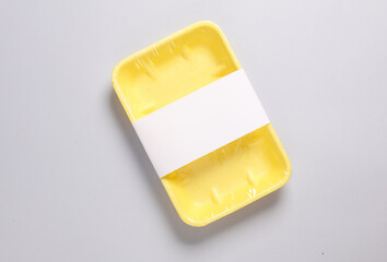 Plastic grocery container for product packaging with a white label in a supermarket on a gray background