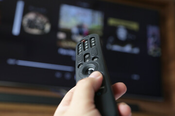 Controle de tv na mão de uma pessoa apontada para abrir o canal Streaming.