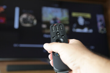 Controle de tv na mão de uma pessoa apontada para abrir o canal Streaming.
